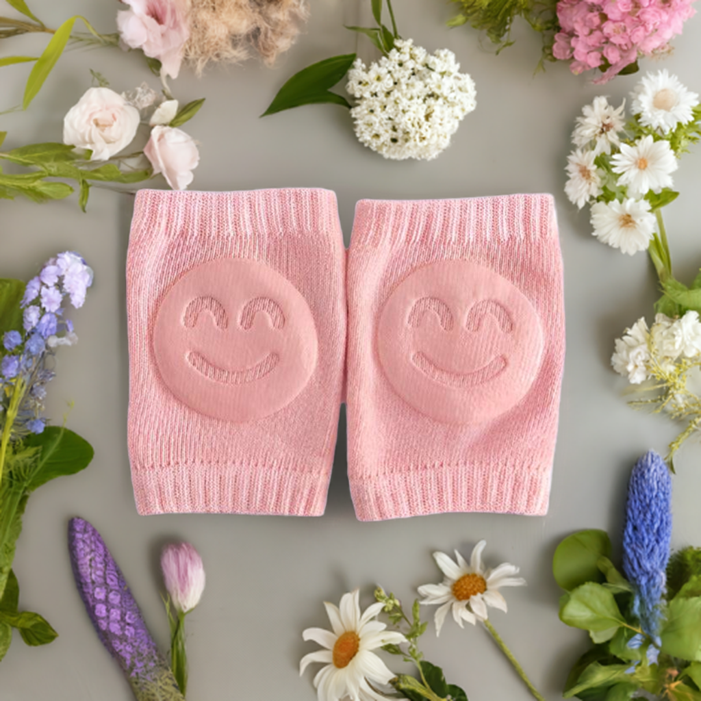 two pink, smiley face knee pads are placed centrally on a light grey background, these knee pads have a textured surface with a cheerful smiley face design embossed on them, pink knee pads, smiley face design, floral arrangement, protective gear, gardening accessories, cheerful design