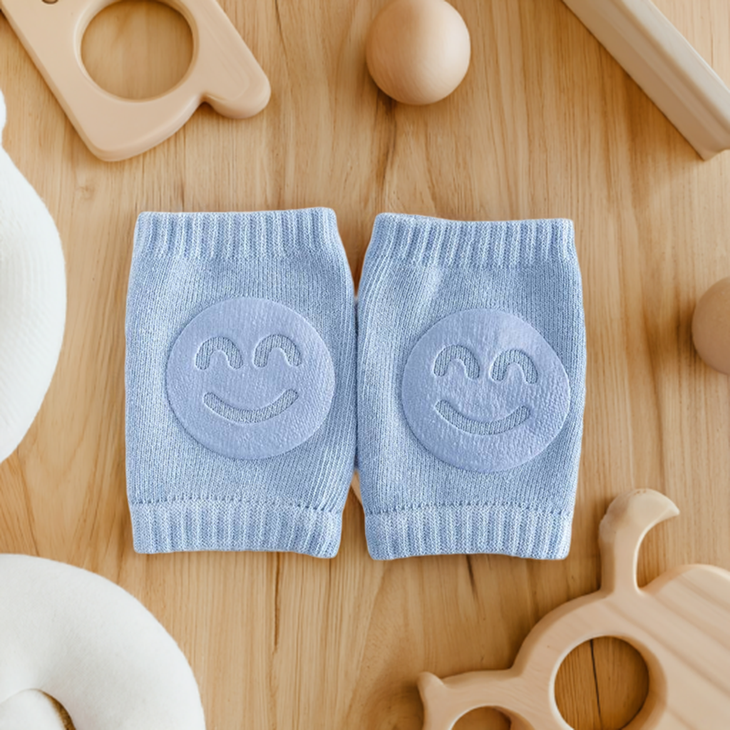 baby knee pads in light blue with smiling faces embroidered on them, baby knee pads, infant safety gear, crawling support, protective wear for babies, embroidered smile design, wooden baby toys, teething rings, child-friendly materials, nursery essentials