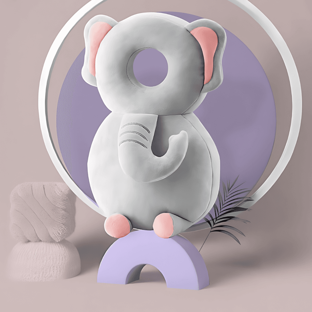 A plush, elephant-shaped cushioned toy with a round opening in the center of its head. The elephant is light gray with pink inner ears, feet, and a curled trunk