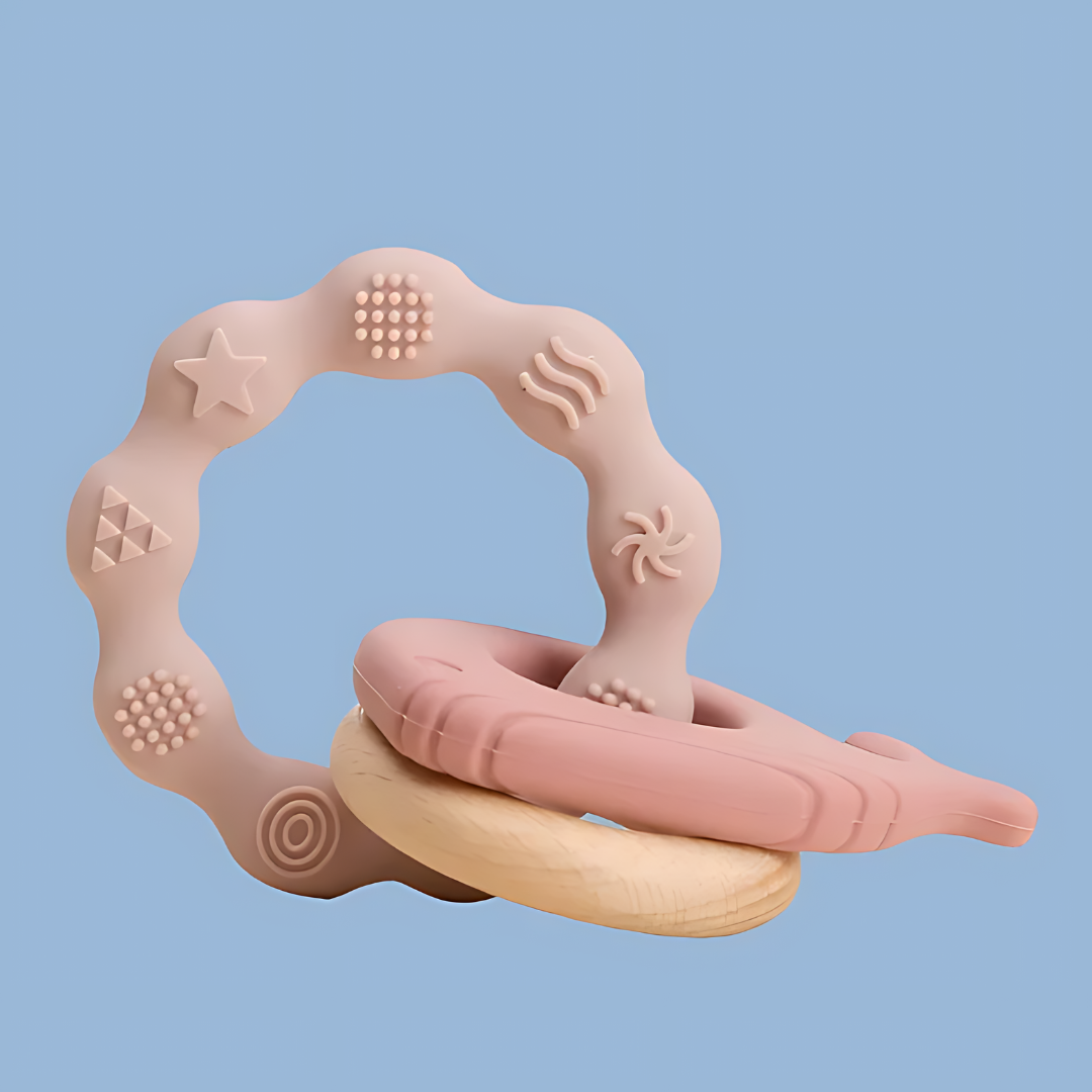 baby teether featuring a whimsical, abstract frame with various shapes and textures, frame includes elements such as stars, dots, swirls, and organic shapes in soft pink and beige tones, the design is playful and modern, suitable for toddlers in the early teething phase, side objects include a ring and whale