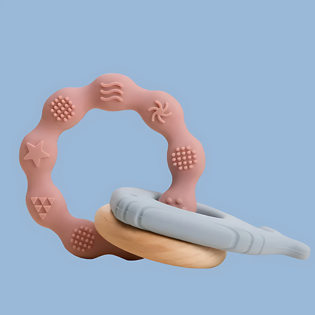 baby teether featuring a whimsical, abstract frame with various shapes and textures, frame includes elements such as stars, dots, swirls, and organic shapes in soft pink and beige tones, the design is playful and modern, suitable for toddlers in the early teething phase, side objects include a ring and whale